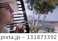 Young Woman Blowing Soap Bubbles While Sitting on Veranda of Country House in Nature 131873392
