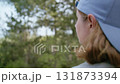 Woman in Cap Standing Outdoors Breathing Deeply While Enjoying Peaceful Nature Walk in Scenic Landscape 131873394