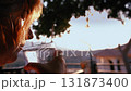 Woman Drinking Refreshing Beverage on Veranda at Sunset 131873400