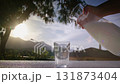 Milk Pouring from Jug into Glass Outdoors with Mountain Sunset View 131873404