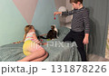 A girl and boy giggling while they interact with a cute kitten on the sofa in their house. 131878226