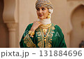 A beautiful woman, dressed in a traditional Omani green kaftan with elaborate gold embroidery, a headscarf, and stunning heavy gold jewelry 131884696