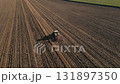 Tractor working on agricultural field, plowed farmland 131897350