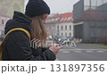 Woman in winter jacket using smartphone on city street 131897356
