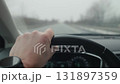 Driver hand on steering wheel, driving car on foggy road 131897359