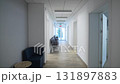 Long corridor stretches toward glass door framed by shine 131897883