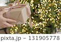 Wrapped presents are exchanged by cheerful hands near shimmering Christmas tree 131905778