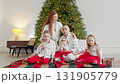 Families gather around Christmas tree, sharing smiles and warm hugs. 131905779