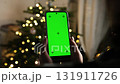 Girl Holds A Smartphone With A Chroma Key Green Screen With Marks Against Christmas Lights At Home 131911726