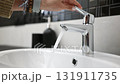 Girl Opens The Bathroom Sink Mixer Tap And Water Flows From The Faucet 131911735
