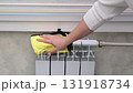 A woman's hand wipes a heating radiator 131918734