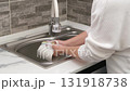 Women's hands washing a white mug in the sink 131918738