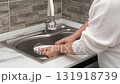 Women's hands washing a white plate in the sink 131918739