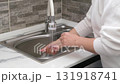 Women's hands washing a white plate in the sink 131918741