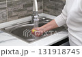 A woman's hands wash a metal pan in the sink 131918745