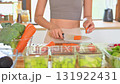 Healthy lifestyle concept with young woman chopping vegetables and organizing colorful produce on kitchen counter 131922431