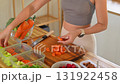 Young woman slicing fresh carrots and preparing ingredients for weekly healthy meal prep at home 131922458