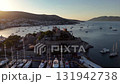 Aerial view of Bodrum Castle and marina in Turkey at sunset, with yachts, calm sea, and white hillside houses glowing in warm evening light. 131942738