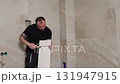 Construction Worker Installing Large Travertine Tiles in Modern Bathroom 131947915
