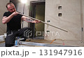 Construction worker holding tile and checking size before cutting it with tile cutter 131947916