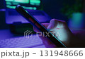 Close up of hand browsing content on a mobile phone in front of a desk 131948666