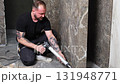 Construction worker applying silicone sealant on tiles in bathroom 131948771