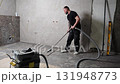 Construction worker vacuuming dust and debris after laying tiles in bathroom 131948773