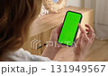 Woman sit use digital tech cell phone with green screen mock up. Hand scroll phone web site, swipe like photos. Girl hold mobile closeup. Chroma key page. Cozy home background. Online app copy space. 131949567