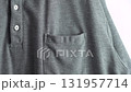 A Hand is attaching a yellow and white guest tag on a guest's pocket. It is a casual gray shirt with a button-down collar. 131957714