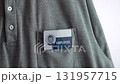 Hand is attaching a blue and white employee tag on a employer's pocket. It is a casual gray shirt with a button-down collar. 131957715