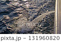 Powerful water jet being pumped out from the side of a moving ferry into the sea, creating white foam and ripples on the ocean surface under sunlight. 131960820