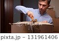 Man unboxing cardboard box with utility knife 131961406