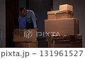 Man moving cardboard boxes during home relocation and packing 131961527