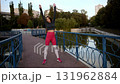 Woman Exercising Outdoors on Bridge, Stretching and Warming Up in Urban Park 131962884