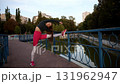 Young Woman Stretching in Urban Park During Morning Exercise Routine 131962947