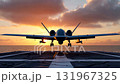 Frontal eye-level view of a twin-engine armed surveillance drone with landing gear extended, approaching an aircraft carrier runway at sunset 131967325