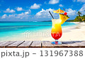 Refreshing layered tropical cocktail with pineapple cherry garnish on wooden table beautiful sunny beach turquoise ocean background 131967388