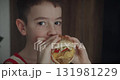 Little boy at home eats burger. Portrait of hungry child Cute little kid eating burger. Hungry child in fast food cafe. Close-up boy eating burger. Hungry child in cafe. Lovely boy 131981229