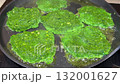 Unusual green spinach or broccoli fritters are fried in a pan. 132001627
