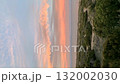 Sunset sky over coastal landscape with vibrant clouds and distant mountains, ideal as background video 132002030