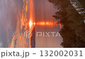 Sunset over calm sea with orange and pink sky, silhouetted trees and distant hills video 132002031