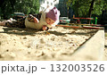 Child exploring sand at a playground while enjoying the sunny weather in a city park 132003526