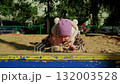 Child exploring sand at a playground while enjoying the sunny weather in a city park 132003528