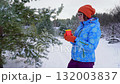 Woman enjoys winter walk sipping hot drink in snowy forest 132003837