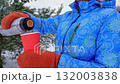Winter warmth, pouring a hot drink from a thermos into a cup on a snowy background 132003838