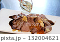 Serving of sliced boiled beef tongue with pickled cucumbers and bell peppers drizzled with olive oil soy sauce and crushed garlic topped with black and white sesame and microgreens on white plate. 132004621