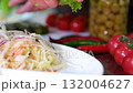 Process preparing and serving traditional sauerkraut with shredded cabbage mixed with salt and carrot arranged plate with red onion showing healthy homemade fermented food rich in natural probiotics. 132004627