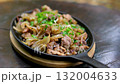 Classic Chinese stir-fried shredded beef with pickled chili, ginger, dried chili, and onions in a black wok, tossed with a green spatula, sizzling in a flavorful kitchen process. 132004633