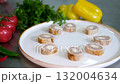 Step by step salad preparation with sliced chicken and liver rolls on a bed of arugula topped with tomato slices black and white sesame and a drizzle of olive oil in a bright kitchen 132004634
