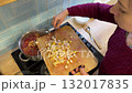 A woman prepares traditional borscht in her kitchen, surrounded by fresh vegetables, as the warm, rich aroma of homemade soup fills the air. 132017835